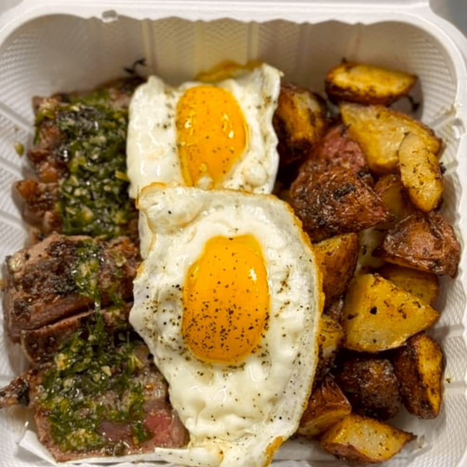 Good Hatch breakfast with steak, two fried eggs, and roasted potatoes in a takeout container.